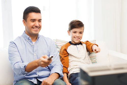 family, people, technology, television and entertainment concept - happy father and son with remote control watching tv at home