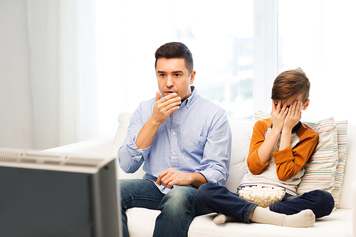 family, people, technology, television and entertainment concept - scared father and son watching horror movie on tv at home