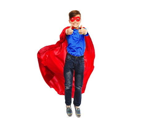 happiness, freedom, childhood, movement and people concept - boy in red super hero cape and mask flying in air and showing thumbs up