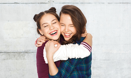 people, emotions, teens and friendship concept - happy smiling pretty teenage girls hugging and laughing over gray concrete wall background