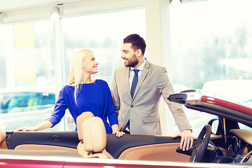 auto business, car sale, consumerism and people concept - happy couple buying car in auto show or salon