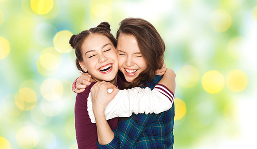people, emotions, teens and friendship concept - happy smiling pretty teenage girls hugging and laughing over green holidays lights background