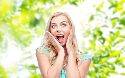 emotions, expressions, summer and people concept - surprised smiling young woman or teenage girl over green natural background