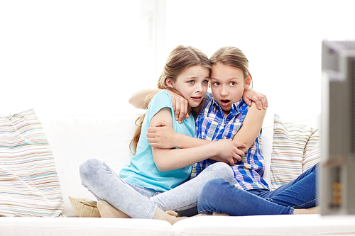 people, children, television, friends and friendship concept - two scared little girls watching horror on tv at home