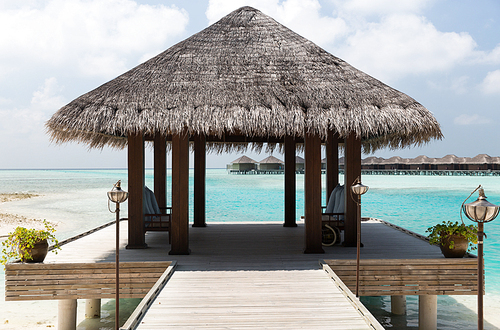 travel, tourism, vacation and summer holidays concept - patio or terrace with canopy on maldives beach sea shore