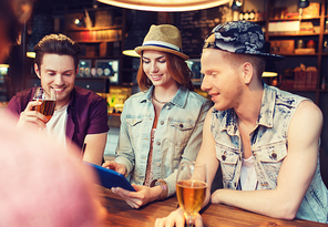 people, leisure, friendship and communication concept - group of happy smiling friends with tablet pc computer and drinks at bar or pub