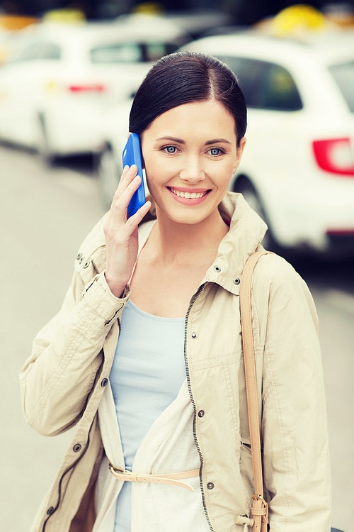 travel, business trip, people and tourism concept - smiling young woman calling and talking on smartphone over taxi station or city street