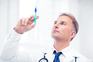 healthcare and medical concept - male doctor holding syringe with injection