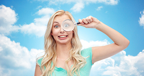 vision, exploration, investigation, education and people concept - happy smiling young woman or teenage girl looking through magnifying glass over blue sky and clouds background