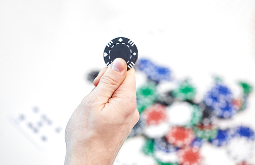 leisure, games, gambling and entertainment - close up of male hand holding casino chip and playing cards at home