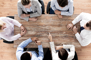 business, people and team work concept - close up of creative team sitting at table and pointing finger to something in office