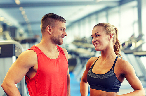 sport, fitness, lifestyle and people concept - smiling man and woman talking in gym