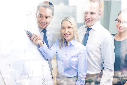 business and office concept - smiling business team with charts on flip board having discussion