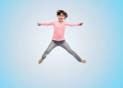 happiness, childhood, freedom, movement and people concept - happy little girl jumping in air over blue background