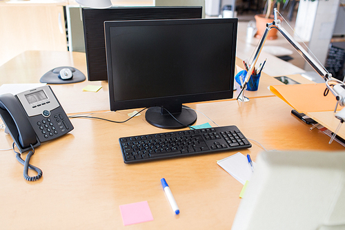 technology, business and advertisement concept - computers with blank black screen on office table