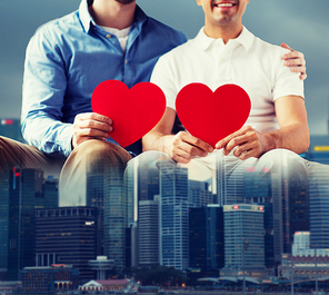 people, homosexuality, same-sex marriage, valentines day and love concept - close up of happy gay male couple with red hearts over city background
