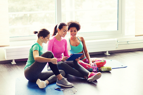 fitness, sport, friendship, technology and lifestyle concept - group of happy women with tablet pc computer in gym