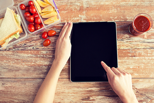 healthy eating, dieting, technology and people concept - close up of woman hands with blank tablet pc computer and food in plastic container on table at home