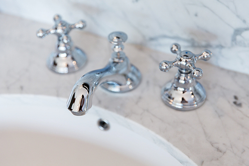 sanitary, plumbing and washing concept - close up of bath tap or faucet at bathroom