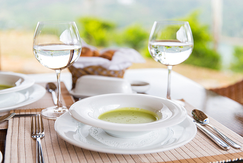 food, cooking and eating concept - close up of creamy soup and water glasses on table at restaurant or home