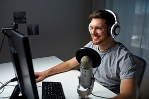 technology, gaming, entertainment, let's play and people concept - happy young man in headset with pc computer playing game at home and streaming playthrough or walkthrough video