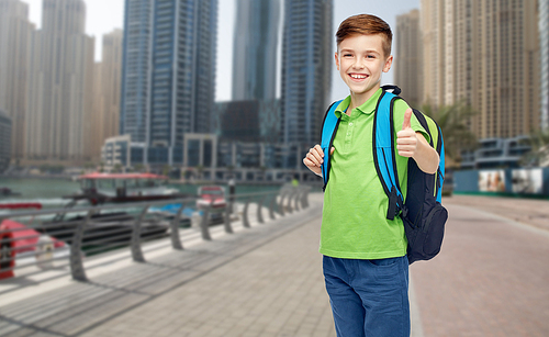 childhood, school, education and people concept - happy smiling student boy with school bag over dubai city street background