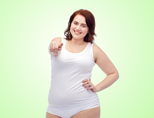 gesture, weight loss and people concept - smiling young plus size woman in underwear pointing finger to you over green natural background