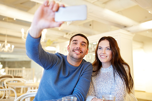 people, technology and dating concept - happy couple taking smartphone selfie at cafe or restaurant