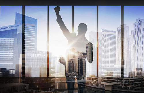 business, success, gesture and people concept - silhouette of happy businessman raising fist and celebrating victory over double exposure office and city background