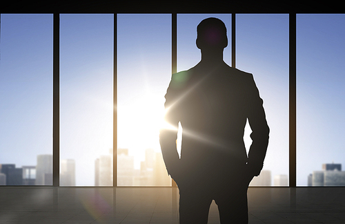 business and people concept - silhouette of business man over office window background