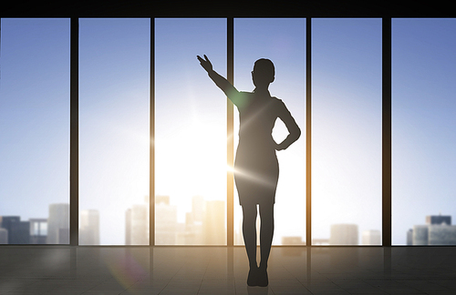 business and people concept - silhouette of woman pointing hand and showing direction over office window background