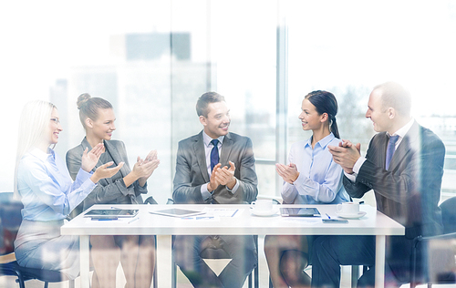 business, technology and office concept - happy business team with laptop computers, documents and coffee clapping hand