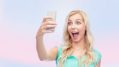 emotions, expressions and people concept - happy smiling young woman or teenage girl taking selfie with smartphone over pink background