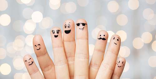 gesture, family, people and body parts concept - close up of two hands showing fingers with smiley faces over holidays lights background