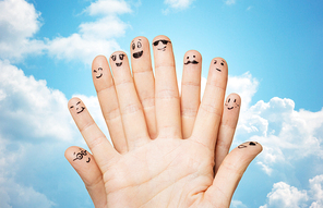 family, people and body parts concept - close up of two hands showing fingers with smiley faces over blue sky and clouds background