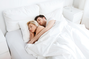 people, rest and relationships concept - happy couple sleeping in bed at home