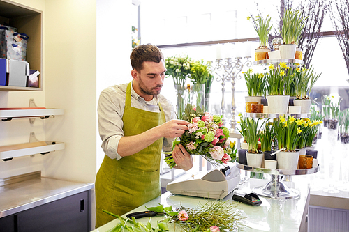 people, business,  and floristry concept - florist man making bunch at flower shop