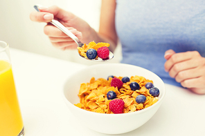 healthy eating, food and people concept - close up of woman eating corn flakes for breakfast at home