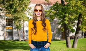 people, education, holidays and fashion concept - happy young woman or teen girl in casual clothes and sunglasses over campus and summer park background