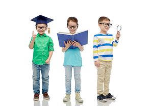 childhood, education, knowledge and people concept - happy little children in eyeglasses with book, magnifying glass and mortar board