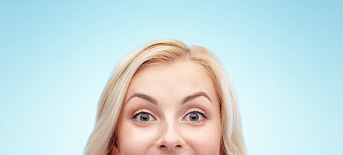 curiosity, advertisement and people concept - happy young woman or teenage girl face over blue background