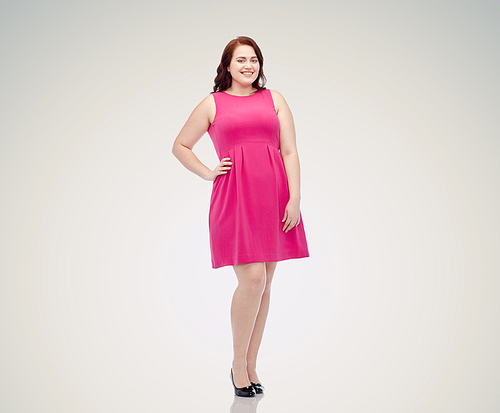 female, gender, portrait and people concept - smiling happy young plus size woman posing in pink dress over gray background