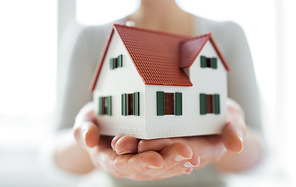 architecture, building, construction, real estate and property concept - close up of hands holding house or home model