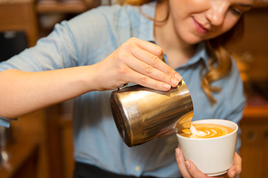equipment, coffee shop, people and technology concept - close up of woman pouring cream to cup of coffee at cafe bar or restaurant kitchen