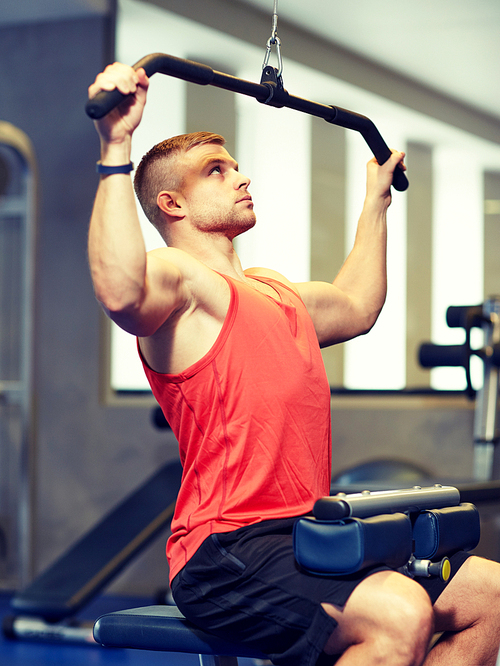sport, fitness, bodybuilding, lifestyle and people concept - man exercising and flexing muscles on cable machine in gym