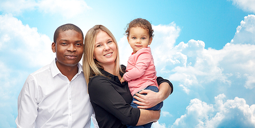 family, children, race and international concept - happy multiracial mother, father and little child over blue sky and clouds background