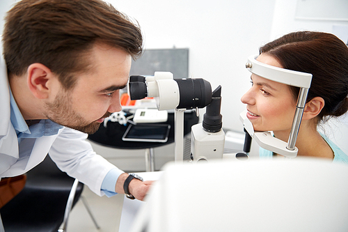 health care, medicine, people, eyesight and technology concept - optometrist with non contact tonometer checking patient intraocular pressure at eye clinic or optics store