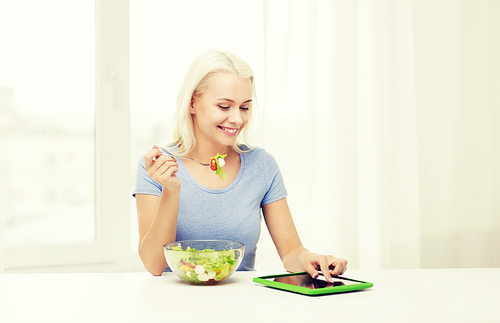 healthy eating, dieting and people concept - smiling young woman with tablet pc computer eating vegetable salad at home