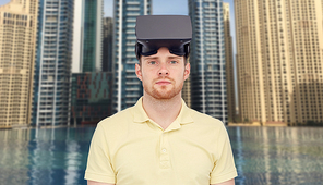 3d technology, virtual reality, entertainment and people concept - young man with virtual reality headset or 3d glasses over dubai city infinity edge pool background