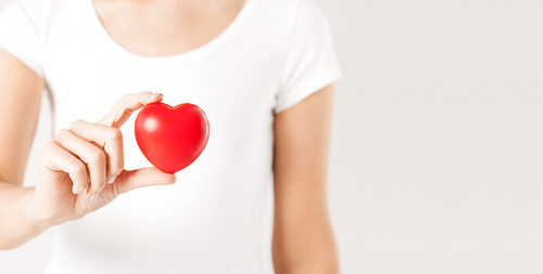health care, medicine and charity concept - close up of woman holding red heart
